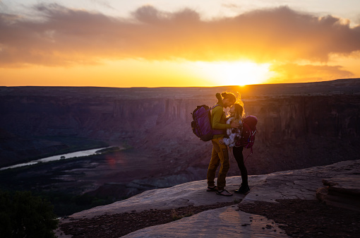 Young couple tender moment while resting from a hike in Moab park in front of a great sunset