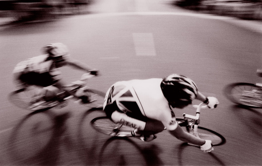 An elevated panning shot of cyclists competing in a road race.