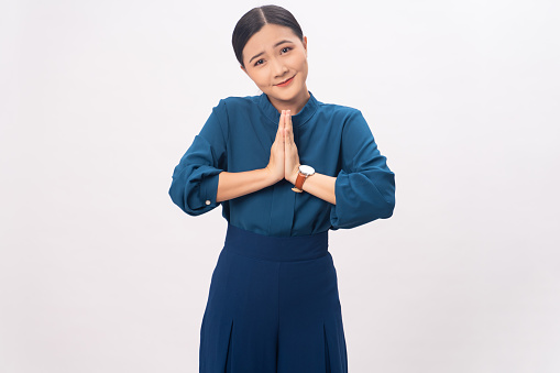 Asian woman guilty holding hands in prayer standing isolated on white background.