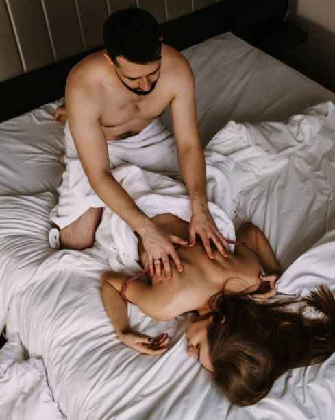 top view of young couple in love in bathrobes lying in bed and cuddling - men sensuality photography high angle view imagens e fotografias de stock