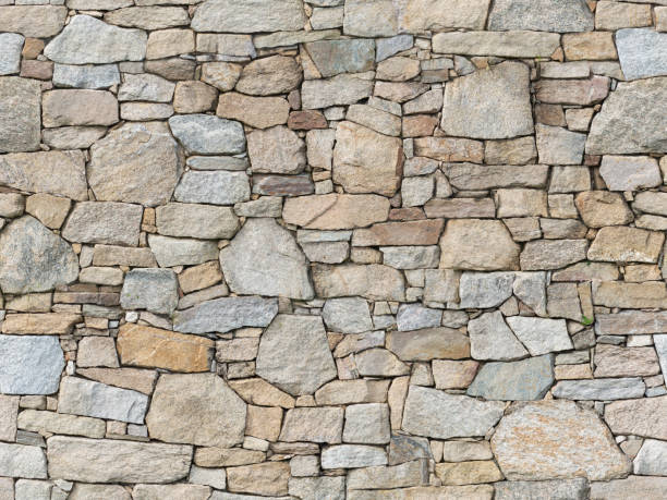 Alpine Stone Veneer Cladding Rock Wall Seamless Texture A seamless texture of rock walling material. A stone veneer that is applied to walls of buildings. natural granite rough stone stock pictures, royalty-free photos & images