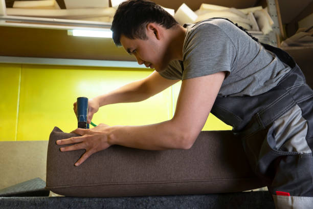 Production of upholstered furniture. Working process with a stapler on a working desk. Manufactory wood shop.