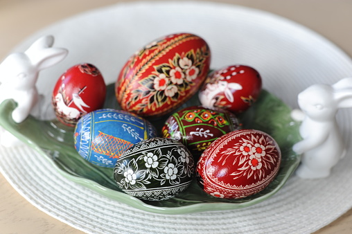 Group of hand painted colorful Easter eggs arranged at the bottom of a white background leaving useful copy space for text and/or logo. Sugar sprinkles and candies complete the composition. High resolution 42Mp studio digital capture taken with Sony A7rII and Sony FE 90mm f2.8 macro G OSS lens