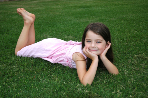 Beautiful five year old girl laying in the yard