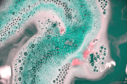 Decorative colorful aroma foam and bubbles in the turquoise bath water. Spa and bodycare