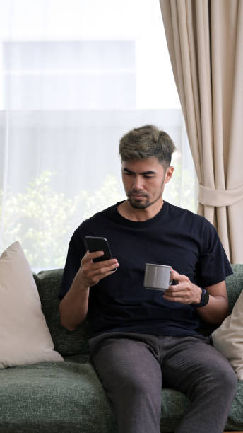istock Man sitting on sofa and drinking hot coffee, spending morning time at home. 1396997186