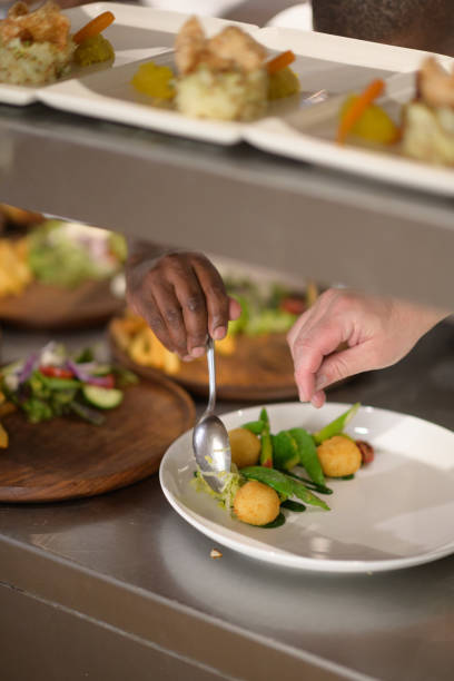 istock African and Caucasian Chefs hands preparing Plates with vegetables on Kitchen counter 1397001131