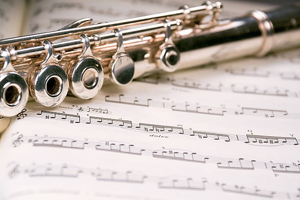Flute across a musical score A used flute rests across an open musical score. Only one line of music is in focus. wolfgang amadeus mozart photos stock pictures, royalty-free photos & images
