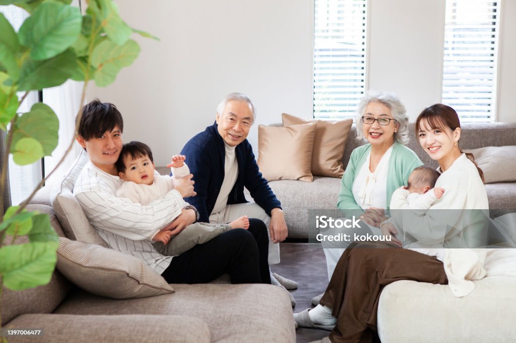 Portrait of asian family relaxing in a modern living room. Three generation family sitting on the sofa in the living room. They are relaxing and enjoying the conversation. Japanese Ethnicity Stock Photo