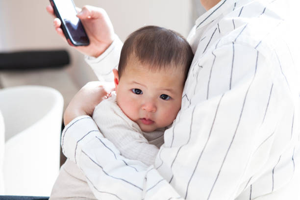 istock Young dad sitting on the sofa and holding his baby while using smartphone. 1397006627