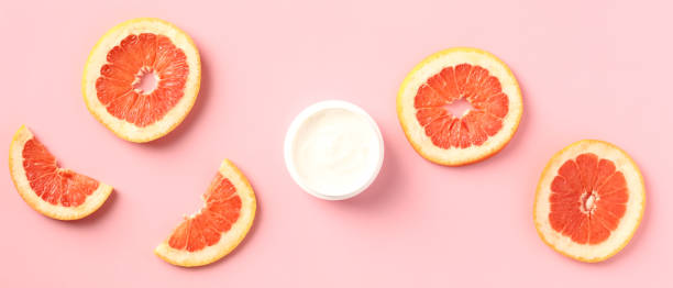 istock Vitamin c body moisturizer cream jar with sliced grapefruit on pink background. Wide banner for beauty salon. 1397008569