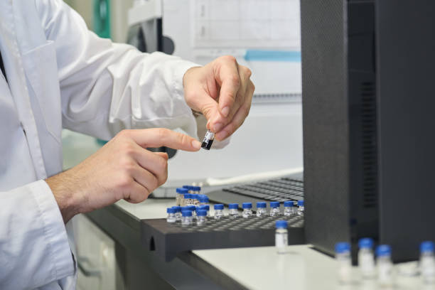 científico en bata de laboratorio colocando vial con muestra en automuestreador de sistema hplc. - hplc fotografías e imágenes de stock