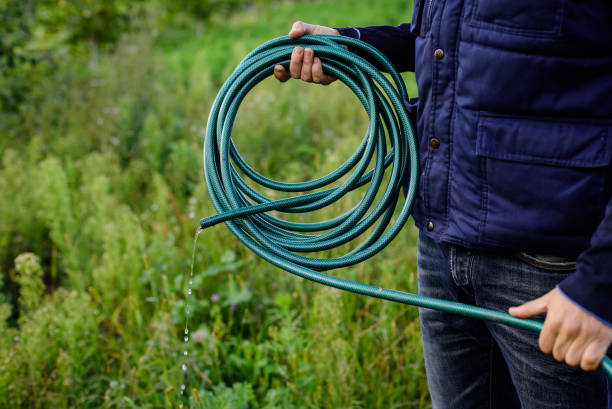 Male hand twists water green garden hose. Male hand twists water green garden hose. garden hose stock pictures, royalty-free photos & images