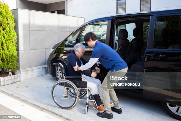 A Senior Man Helped By A Young Male Carer Out Of Car And Into Wheelchair Stock Photo - Download Image Now