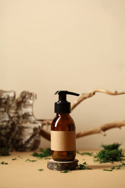 istock Brown amber glass bottle with label mockup on beige table with birch bark, tree branch, moss 1397009868