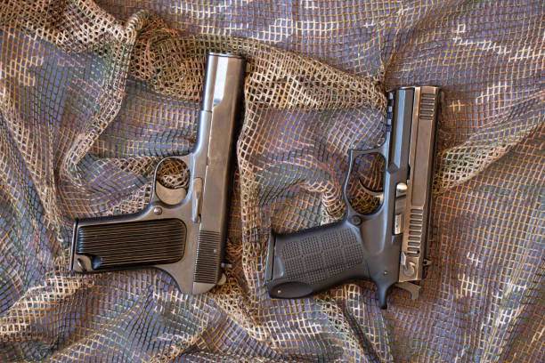 istock Two combat pistols lie on a camouflage protective net, military weapon 1397010472