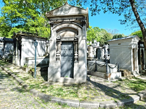 Père Lachaise Cemetery (formerly cimetière de l'Est) is the largest cemetery in Paris. With more than 3.5 million visitors annually, it is the most visited necropolis in the world. The image shows several graves captured during springtime.