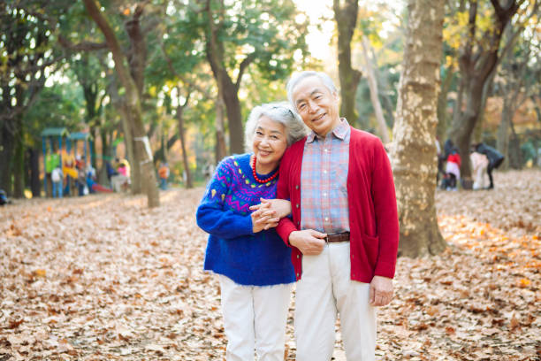 portrait of a senior couple smiling in the park. - couple walking old middle imagens e fotografias de stock