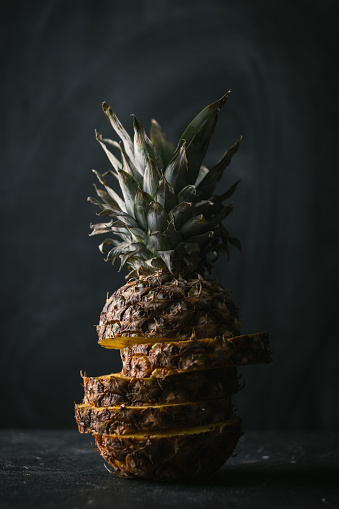 ripe pineapple cut into pieces on a black background