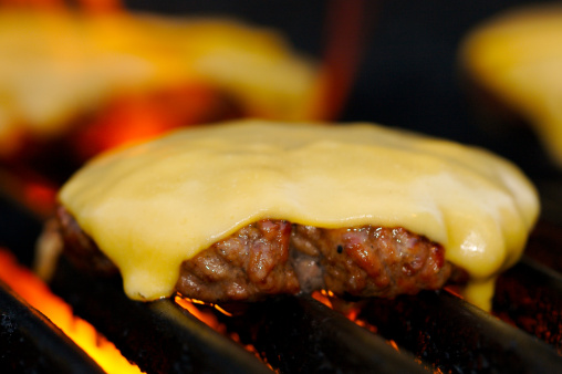 Cheeseburger on the Grill with Small Flame in Background
