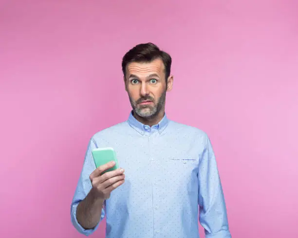 Photo of Shocked man holding mobile phone