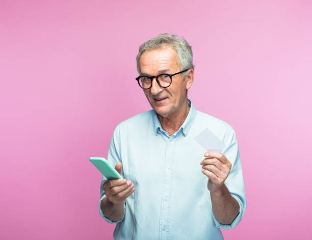 Elderly man holding smart phone and credit card