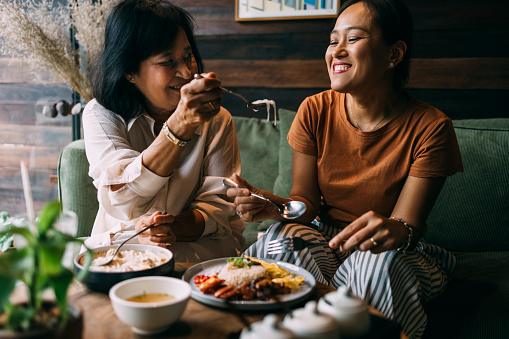 Asian mother sharing her food with her daughter.