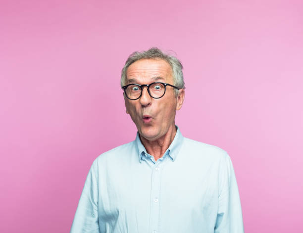 Shocked retired elderly man making face Portrait of shocked retired elderly man making face over pink background making a face stock pictures, royalty-free photos & images