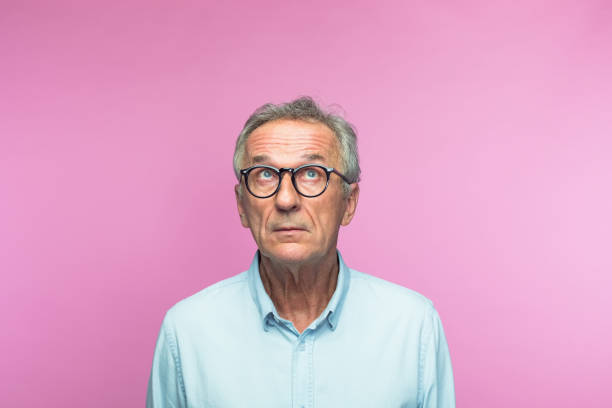 Thoughtful retired elderly man looking up stock photo
