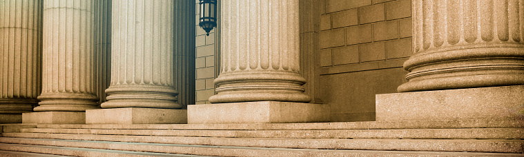 Steps lead toward a row of greek columns that stand in the portico of a courthouse.