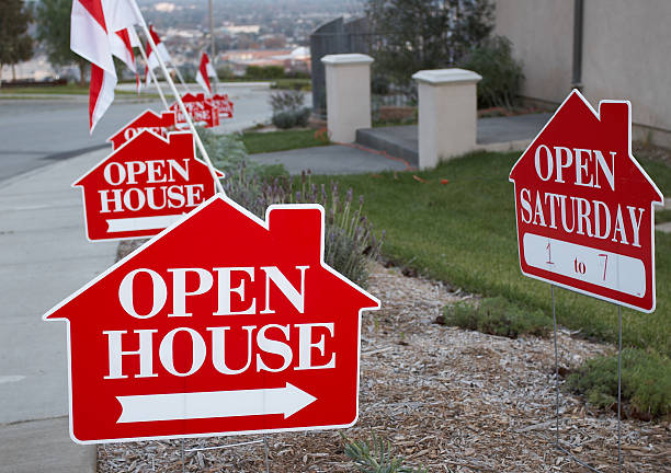 Red and white open house sign close-up with more signs in the background.