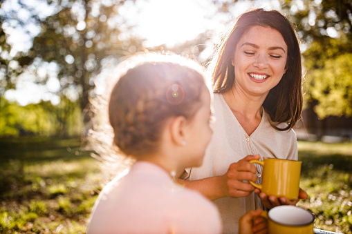 Young happy mother communicating with her daughter while enjoying in spring day.