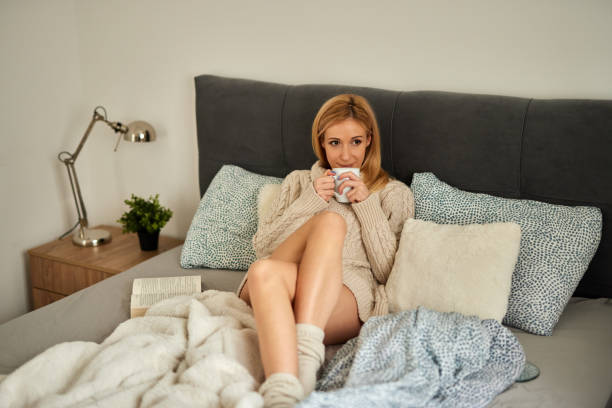 istock Young woman enjoying a good book at home in bed while drinking coffee 1397021899