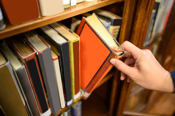 istock Male hand picking old book from bookshelf 1397023216