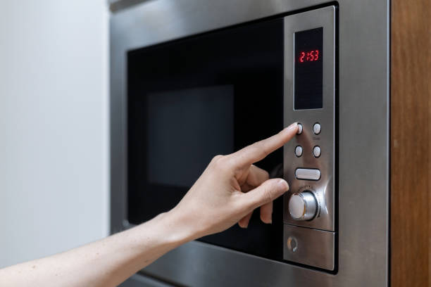 istock Person's hand pressing microwave oven button to start defrosting food 1397025069
