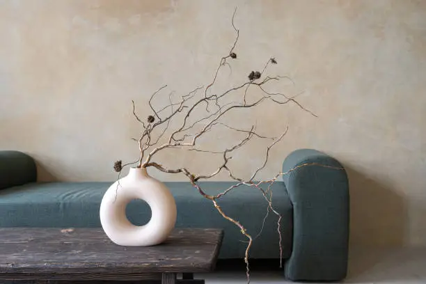 Photo of Dry branches in ceramic vase on vintage table