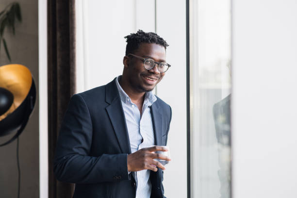 istock Smiling young black man in a suit, holding a glass 1397028858