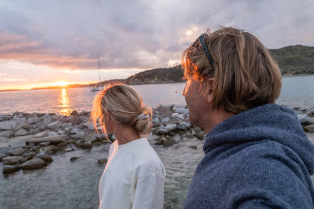 pareja joven junto al mar feliz de estar de vacaciones - blond hair overcast sun sky fotografías e imágenes de stock