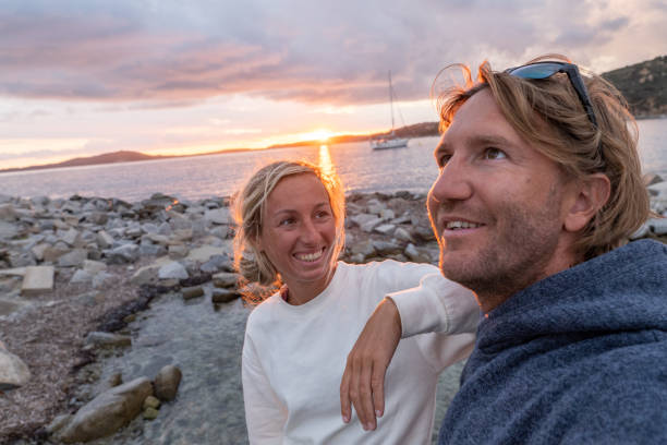 pareja joven junto al mar feliz de estar de vacaciones - blond hair overcast sun sky fotografías e imágenes de stock