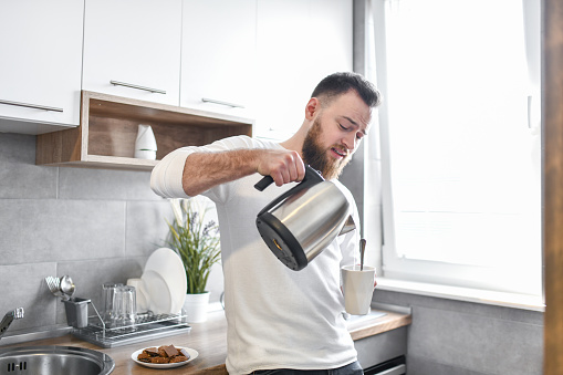 Handsome Male Pouring Himself Coffee In Kitchen