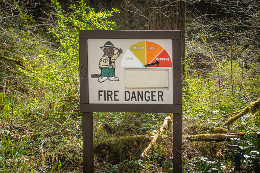 Sign depicting fire danger index in forest with warning set at extreme fire danger.