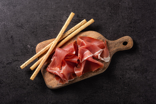 Spanish serrano ham on black slate background