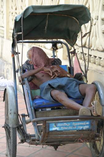 Driver catching up on sleep in his own Cyclos  during a quiet time in Phnom Penh.