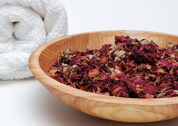 wooden bowl full of rose petals with a rolled up white towel
