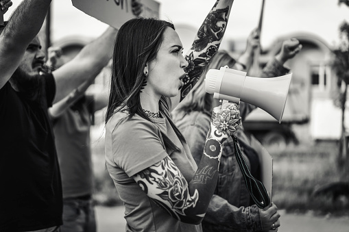 Young tattooed woman shouting through megaphone during a demonstration in the street