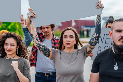 Group of people protesting in the street with blank placard