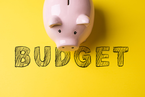 Piggy bank in front of Budget word hand-written on yellow background