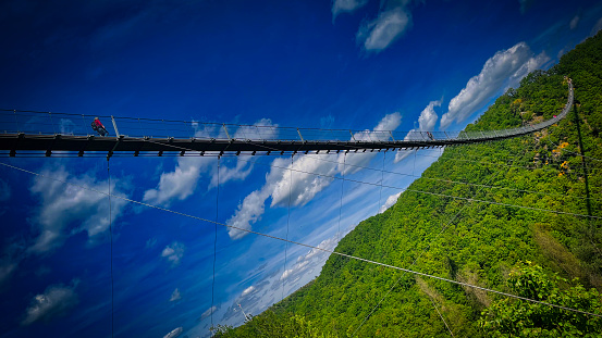 10. Mai 2020, Germany: The Geierlay is a suspension bridge in the low mountain range of the Hunsrück in western Germany. It was opened in 2015. It has a span range of 360 metres (1,180 ft) and is up to 100 metres (330 ft) above ground. On both sides of the bridge are the villages of Mörsdorf and Sosberg. A stream named Mörsdorfer Bach runs through the valley below the bridge. The nearest city is Kastellaun 8 km eastwards. The state capital Mainz is 66 km towards east.\n\nThe bridge has a weight of 57 tons and can support 50 tons. It is a pedestrians only bridge. Until 2020, bridge was free for tourists.  Due to the coronavirus pandemic, a fee of 5 euros per person was introduced for crossing the bridge. The crossing is only possible from the side of the village of Mörsdorf. Twenty per cent of all visitors visiting the bridge do not cross it. The bridge site is within the Top 100 sightseeing destinations in Germany.