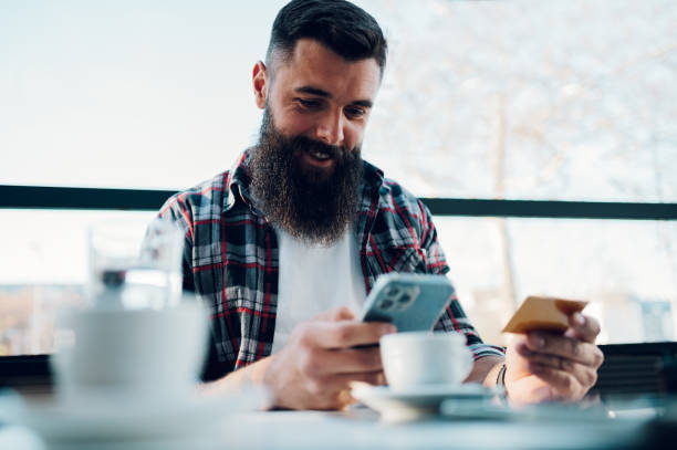 istock Bearded man using smartphone and a credit card in a cafe or restaurant 1397038819