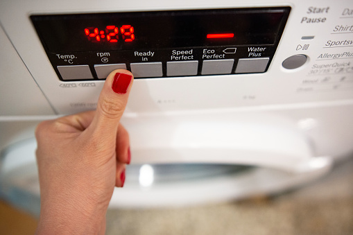 Young woman select the program on washer